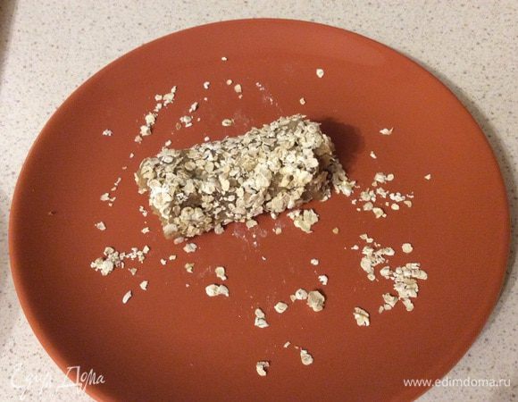 Хлеб аккуратно сворачиваем в рулет, обмакиваем во взбитое яйцо и обваливаем в овсяных хлопьях (у меня быстрого приготовления). 