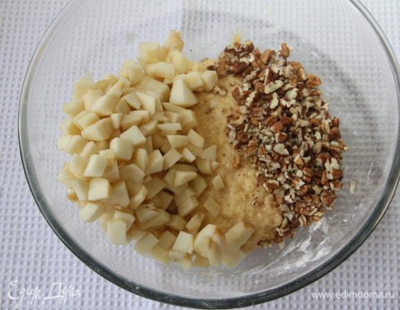 Очистить яблоки, удалить сердцевину и нарезать их мелким кубиком. Орехи порубить. Добавить яблоки и орехи в тесто, перемешать.