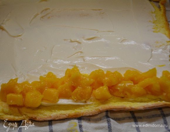 Остывший бисквит развернуть и смазать сметанным кремом. По краю выложить кусочки манго. Свернуть в тугой рулет, начиная от края, где манго. Убрать в холодильник, чтобы рулет хорошо пропитался.