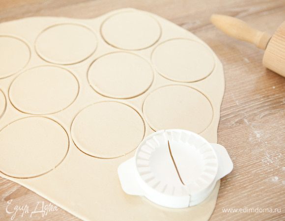 Раскатываем тесто тонким пластом толщиной 2 мм. Поверхность заранее припорошив мукой. Вырезаем стаканом кружки, я использую специальное приспособление для вареников. Замороженные ягоды высыпаем в дуршлаг и даем оттаять.