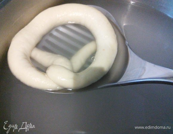 С утра вынуть брецели для аклиматизации на 30 мин., предварительно сняв пленку. За это время сделаем содовый раствор. Нагреть воду в кастрюле до 80°С, уменьшить огонь, добавить соду и тщательно размешать. На 1,5 литра воды необходимо  2 ст. л. пищевой соды. Теперь аккуратно окунуть брецели (по одному с помощью шумовки) в раствор соды на 20 — 25 секунд.