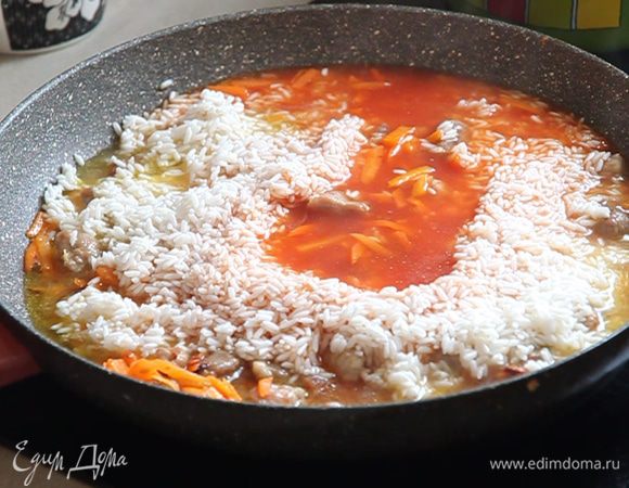 В рис вливаем нашу «болтушку» с томатом (повторюсь, что томат можно не добавлять, в классическом рецепте плова томата нет). Всё хорошо разравниваем и добавляем кипяченную воду, чтобы сверху риса остался 1 сантиметр воды. Кладём два зубчика чеснока, солим, и ещё раз аккуратно перемешиваем.