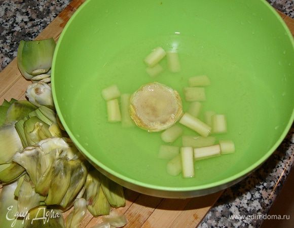 В емкость с водой, куда выдавлен сок половины лимона, немедленно опускаем нарезанный на брусочки стебель и очищенную сердцевину артишока. Артишок очень быстро темнеет. 
