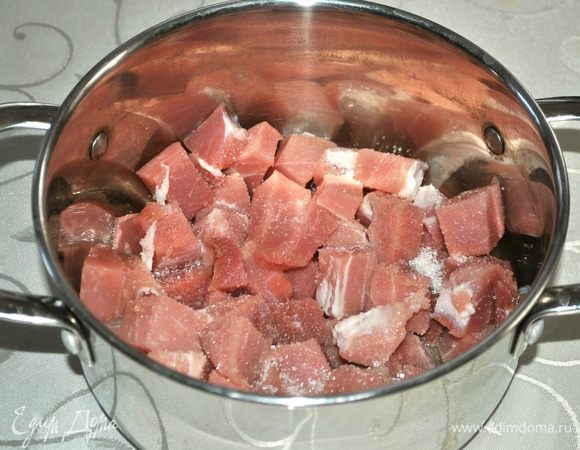 На дно кастрюли с толстым дном наливаем масло. Мясо режем небольшими кусочками. Кладем в масло, сверху посыпаем сахаром. Сахар делает мясо мягче.