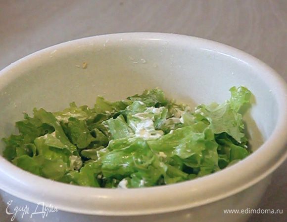В листья салата добавляем сметану и перемешиваем.