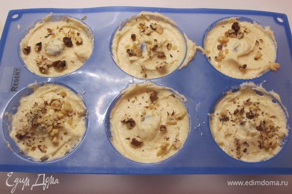 Выложить тесто в формочки, посыпать мелко измельченными орехами, можно вмешать орехи в тесто. Я часть вмешала в тесто, часть поверх теста.