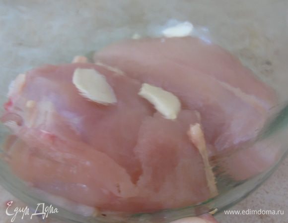 На дно кладем куриное филе, его солить не надо, оно будет готовится в  соленом соке, что пустит мясо и этого будет достаточно. Сверху кладем пару пластинок чеснока.