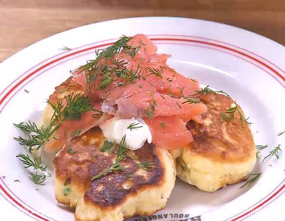 На готовые оладьи выложить понемногу сметаны и семги, затем посыпать укропом.