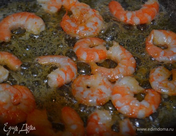 Сковороду разогреть, вылить оливковое масло и раздавить туда один зубчик чеснока, немного поджарить его, чтобы он отдал весь аромат маслу. Убрать чеснок и выложить очищенные креветки. Обжарить 1 минуту и убрать на отдельную тарелку.