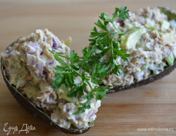 Добавить заправку в салат. Перемешать. Разделить на 2 равные части и разложить в кожуру авокадо горкой. Украсить зеленью по желанию.