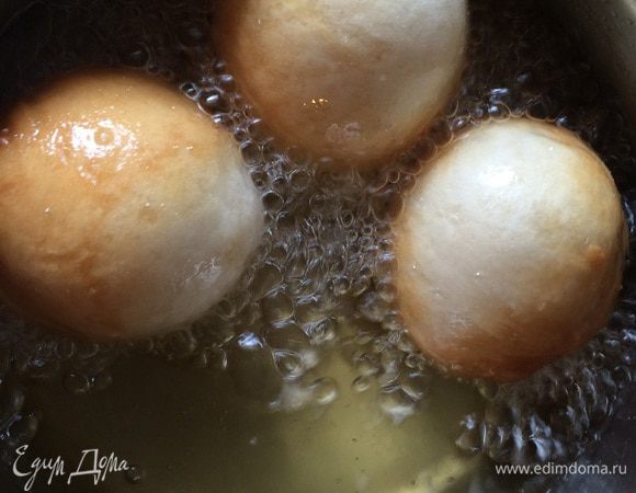 Разогрейте в сотейнике масло. Обомните тесто. Смазав ладони растительным маслом, возьмите небольшую порцию теста в левую руку. Сожмите так, чтобы в верхней части руки (между большим и указательным пальцами) образовался шарик размером с грецкий орех. Осторожно опустите шарик в кипящее масло. Обжаривайте кусочки теста в сотейнике 2-3 минуты или до появления золотистого цвета. Затем перекладывайте шумовкой на бумажные полотенца. Окуните горячие пончики в сироп.