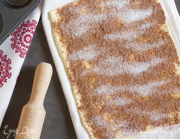 В миске соедините сахар и какао порошок. Растопите сливочное масло. Тесто раскатайте на присыпанной мукой поверхности в прямоугольник 30х40 мм. Смажьте сливочным маслом и выложите сахарную начинку, распределив равномерно по поверхности листа.