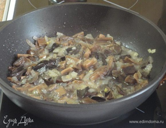 Луковицу нарезать мелко и обжарить до прозрачности на оливковом масле. Добавить нарезанные грибы, перемешать и потушить пару минут.