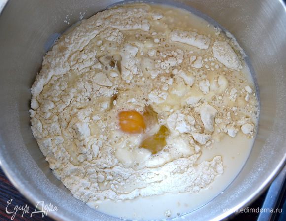 В большую миску всыпать просеянную муку, щепотку соли и оставшийся сахар. (Хочу обратить ваше внимание, что по рецепту-оригиналу идёт 300 г муки. Но, за те несколько раз, что я пекла эти булочки у меня уходило ровно 270 г. Думаю, что зависит от муки, поэтому ориентируйтесь сами по консистенции теста, оно должно стать гладким и эластичным после замеса). Добавить дрожжи, яйцо и начать вымешивать тесто. В процессе вывешивания добавить кусочками размягченное сливочное масло.