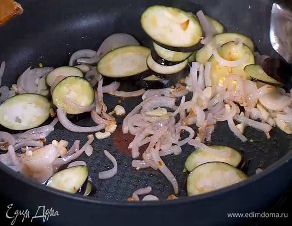 Баклажан нарезать тонкими кружками, выложить в сковороду с луком и чесноком, влить еще пару чайных ложек оливкового масла и все обжарить.