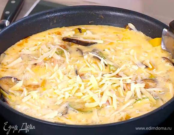 В сковороду с овощами добавить ветчину, сверху вылить яично-молочную массу и посыпать натертым сыром.