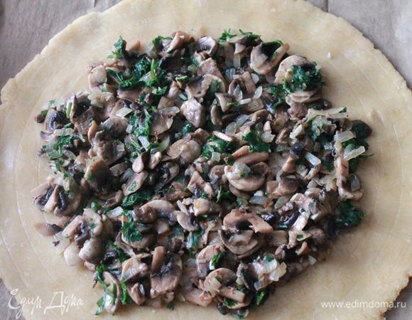 На лепешку, отступая от края см 3, выкладываем начинку из грибов. 