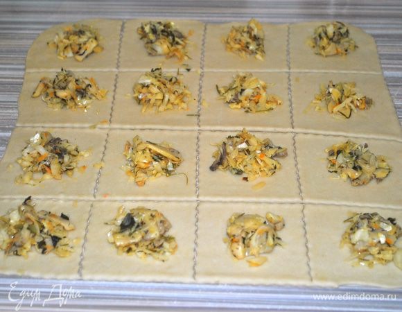 Тесто делим на 2 части. Каждую часть раскатываем в прямоугольный пласт. Делим на одинаковые квадраты. Раскладываем начинку.