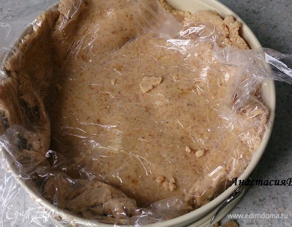 Тесто разделить на 2 части. Половину раскатать между слоями пищевой пленки, снять один слой, выложить в форму и убрать второй верхний слой. Тесто прижать к краям формы. 