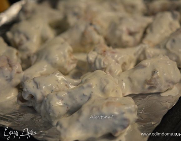 Достать крылышки из духовки. Воду слить. Приготовить противень с фольгой для выпечки. Смазать маслом. Куриные крылышки окунать в соус и выкладывать на противень. Поставить в горячую духовку на 25 мин.