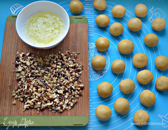 После охлаждения отсоедините по небольшому кусочку теста и скатайте шарик величиной с грецкий орех. Всего должно получиться 22-24 шт. Белки слегка взбейте вилкой. Орехи крупно порубите. Каждый шарик обмакните вначале в белок, а затем равномерно обваляйте в орехах, слегка прижимая их к тесту.