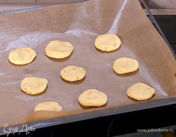 Сформировать из теста небольшие лепешки и выложить на противень, выстеленный бумагой для выпечки.