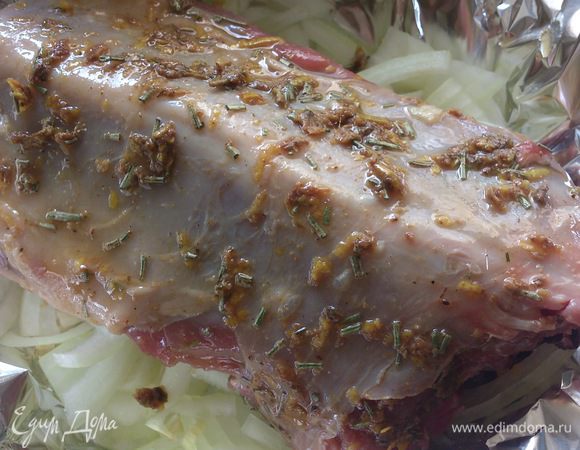 Чеснок разрезать на половинки. В мясе сделать надрезы и нашпиговать чесноком. Смазать мясо маринадом. Положить его сверху луковой подушки.