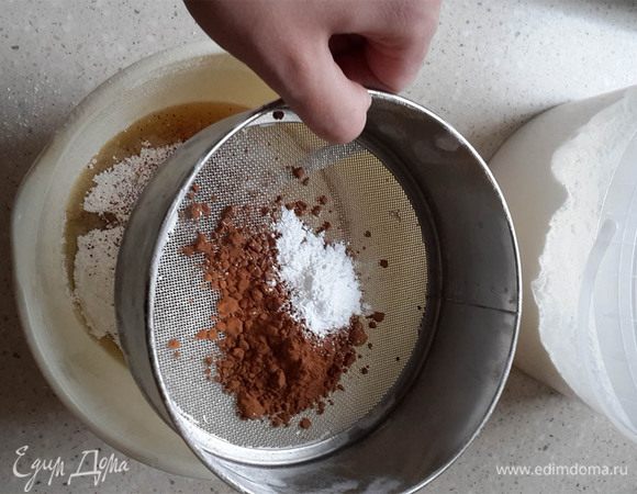 Немного остудить, перелить в миску. Добавить просеянную муку, разрыхлитель и какао.