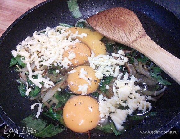 В остывший шпинат с луком разбить яйца, посолить, поперчить, добавить сыр (немного сыра оставить на посыпку), разболтать. 