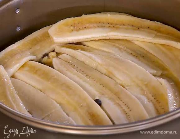 Посыпать корж с маслом частью шоколадных капель, небольшим количеством сахара и выложить плотным слоем ломтики бананов.