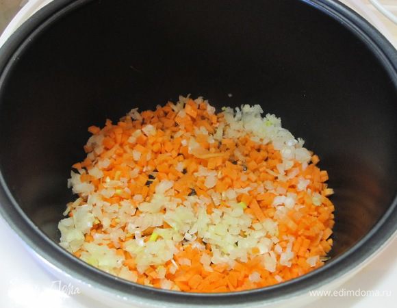 В чашу мультиварки налить 2 столовые ложки растительного масла, выложить нарезанные лук и морковь.