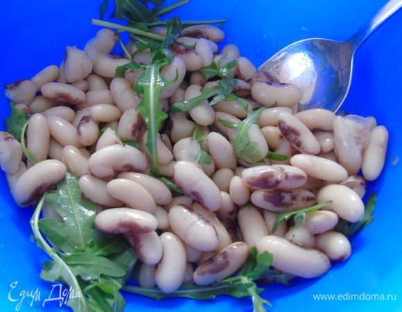 К фасоли добавьте руколу и перемешайте.