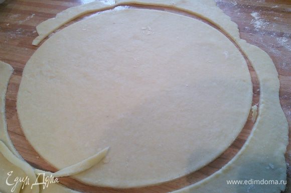 Приблизительно 1/4 часть теста отставить в сторону (это будет "крышка" пирога). На посыпанной мукой поверхности раскатать тесто, выдавить донышком от разъемной формы (26 см в диаметре) круг. Саму форму выложить пергаментом.