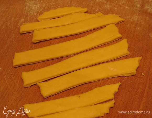 Раскатываем кусочек теста желтого цвета и кусочек красного на хорошо присыпанной мукой поверхности. Нарезаем на полоски.