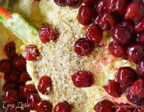 Апельсин помыть, обдать кипятком и снять цедру. Вишню разморозить и слить лишний сок.
Масло комнатной температуры взбить с сахарной пудрой до пышной массы. Добавить по одному яйцу и снова взбить до однородности. Добавить сметану и цедру, всыпать муку с разрыхлителем частями и снова взбить. В конце добавить молотые орехи, тертую цедру и вишню. Аккуратно перемешать.