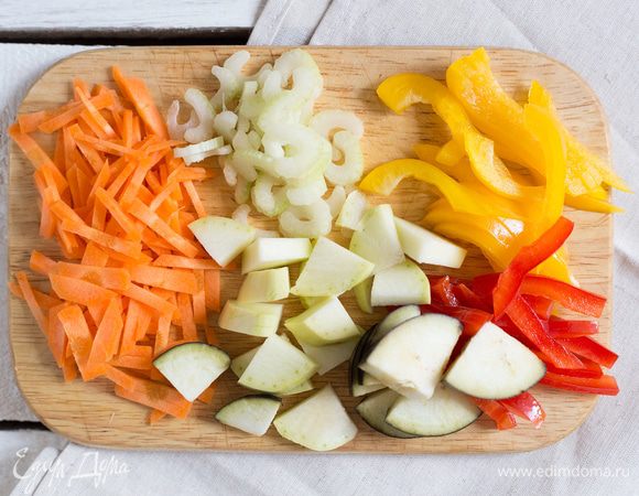 Разогрейте духовку до 200°C. Крупно нарежьте кабачок, баклажан и морковь. Порубите стебли сельдерея и тонко нарежьте красный и желтый перец.