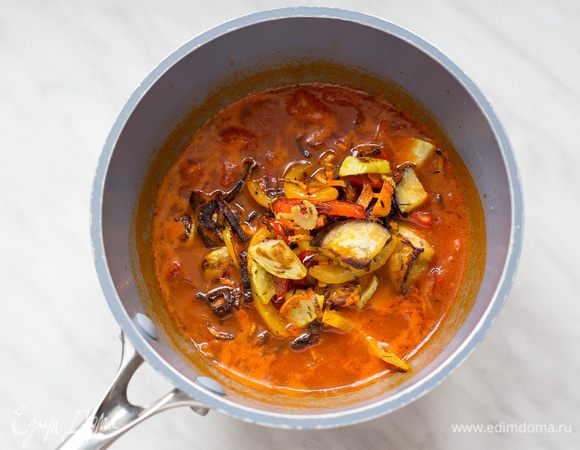 Добавьте томаты и 400 мл бульона. Доведите до кипения и тушите на небольшом огне 20 минут. Достаньте овощи из духовки, выложите в соус, перемешайте и тушите еще 10 минут.