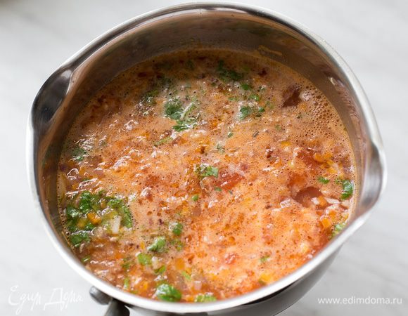 Добавьте томаты, половину чеснока, овощной бульон, кускус, кумина и кинзу.