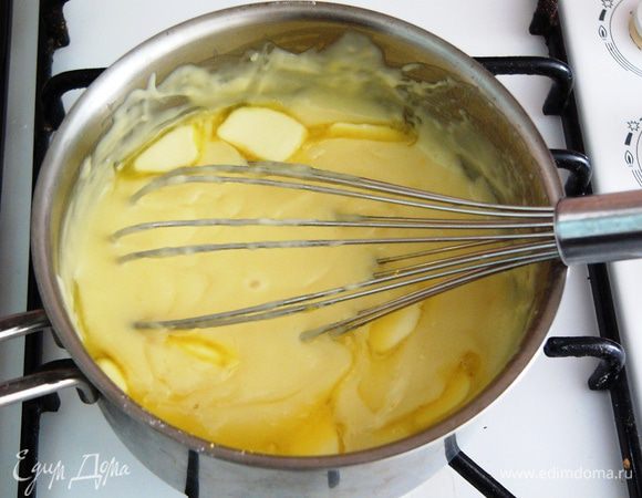 Немного остужаем крем. Чтобы не образовалась корка на поверхности, продолжаем постоянно помешивать крем венчиком. Когда температура крема перестанет быть обжигающей и станет терпима для пальца, вводим сливочное масло до полного его растворения. Хорошо перемешиваем.