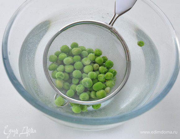 Замороженный зеленый горошек (не размораживая) поместить в кипящую воду на 3 минуты, затем откинуть на сито и сразу обдать ледяной водой, чтобы остановить процесс варки.