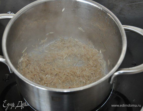 В кастрюле нагреть растительное масло, засыпать рис. Помешивая, прогреть рис на среднем огне. Залить рис кипятком из расчета 3 части воды к 1 части риса, посолить, перемешать, убавить огонь до минимального и варить до готовности около 25 минут. Готовый рис переложить в тарелку, взрыхлить вилкой и остудить до комнатной температуры.