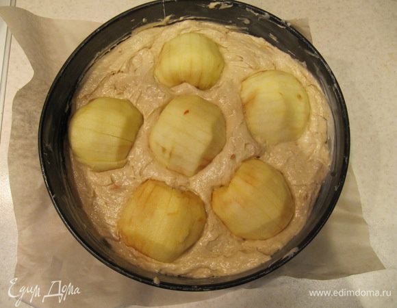 Надрезанные половинки яблоки укладываем поверх теста и слегка вдавливаем в него.