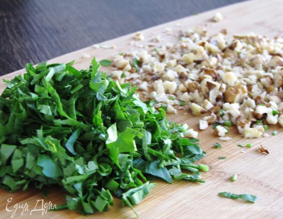 Тем временем петрушку мелко порубить, грецкие орехи измельчить с помощью ножа не в очень мелкую крошку.