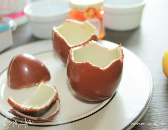 Снимаем обертки с шоколадных яиц, разогреваем лезвие острого ножа и осторожно зигзагом надрезаем скорлупку в верхней части яйца. Аккуратно снимаем "крышечку" и откладываем в сторону. Сюрприз отдаем детям) 