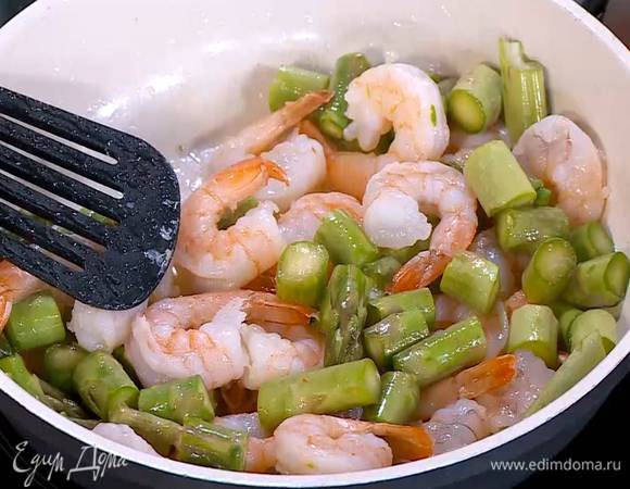Разогреть в сковороде оливковое масло и обжарить размороженные креветки почти до готовности, затем добавить спаржу и обжаривать все еще 3‒4 минуты.