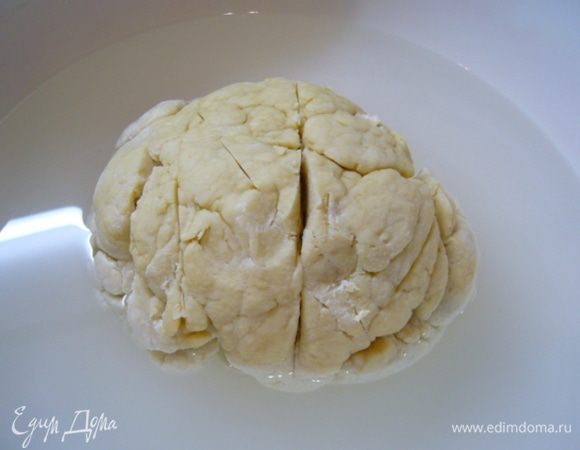 Влить сливки с дрожжами, замесить тугое тесто. Сформировать из него шар. Сделать неглубокие надрезы по кругу острым ножом.
Поместить в большую емкость. Влить в емкость 2 л теплой (40°C) кипяченой воды. Закрыть и поставить на 1 час подходить.
Опара возьмет часть влаги, увеличится в объеме.
Лишнюю воду слить.
