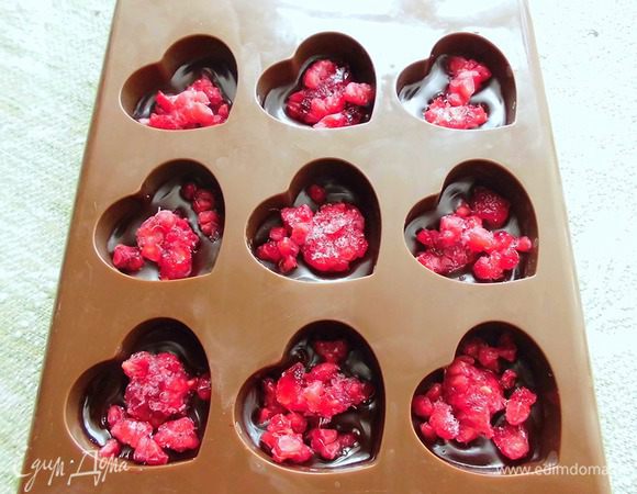 Полученную массу разлить в формочки для шоколадных конфет. Лучше всего брать силиконовую форму, тогда конфеты будут легче выниматься. Заполнить каждую ячейку шоколадом где-то наполовину. Сверху разложить малину. Чем больше малины, тем вкуснее!  