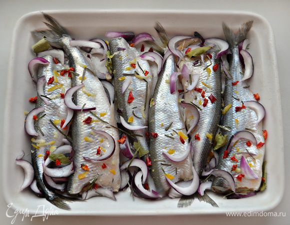 Рыбу слегка натрите солью, сбрызните соком лимона. В смазанную маслом форму положите часть лука, сверху — корюшку. Приправьте рыбу иголочками розмарина, лимонной цедрой, хлопьями сладкой красной паприки и присыпьте  оставшимся красным луком. Если у вас есть сухие листья лайма, то пару небольших листиков сюда также прекрасно подойдут.