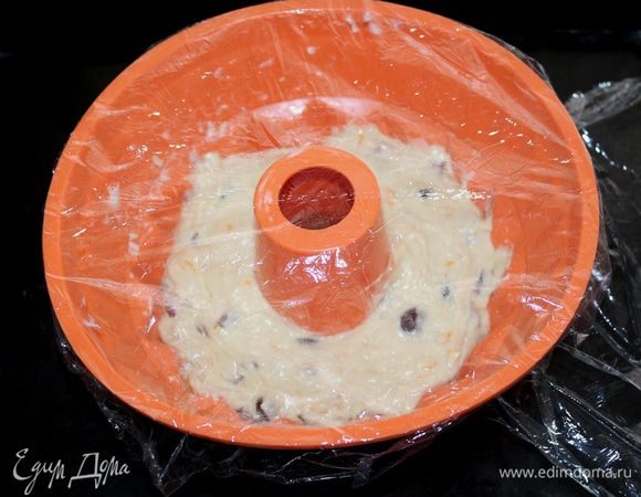 Переложите клейкое тесто в форму и разровняйте поверхность. Тесто заполнит чуть больше половины емкости. Накройте форму пищевой пленкой и поставьте на противень  подходить в теплое место на 1-1,20 минут.
