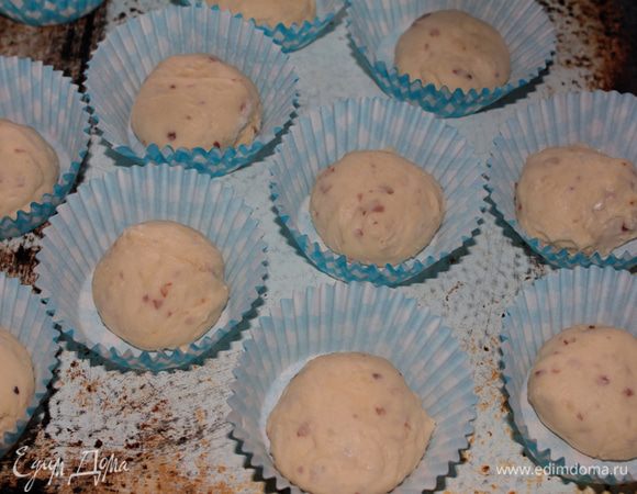 После того, как тесто поднимется вновь, смазав ладони маслом, подмять его. Присыпать небольшим количеством муки и сформовать колобочки размером чуть больше грецкого ореха и выложить в индивидуальные формочки для кексов и мафинов.